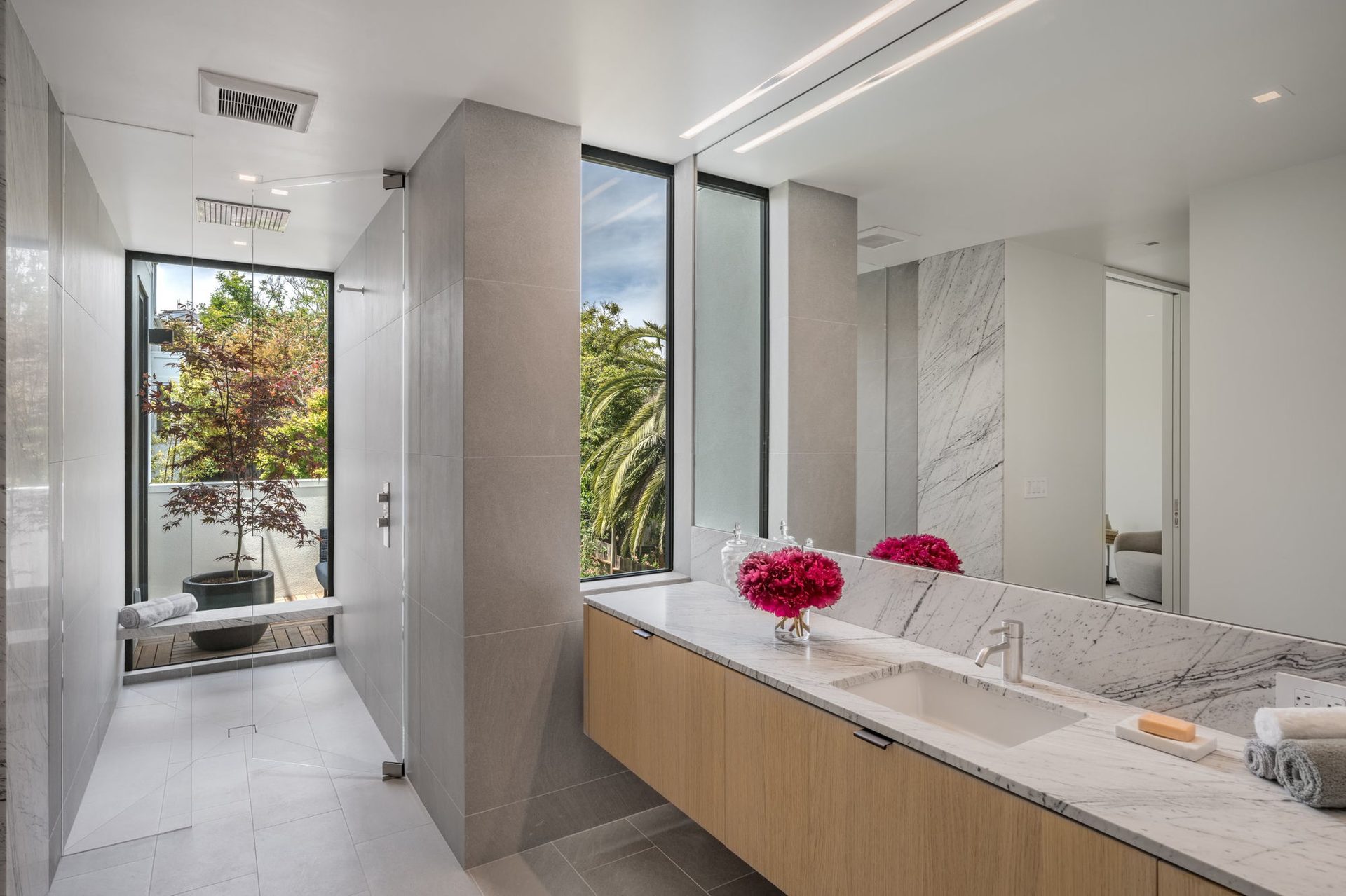 Primary bath with marble vanity and garden view